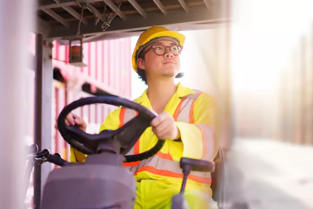 forklift driver working on a digital tablet at container shipyard